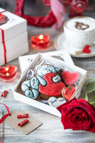Fototapeta Naklejka Na Ścianę i Meble -  Cookies or gingerbread cookies in a gift box with a red ribbon on a wooden table. Valentine's Day.