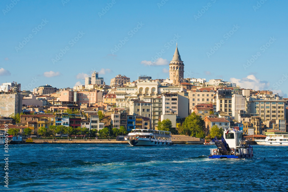 Fototapeta premium Boats ferry commuters and tourists to and from the Beyoglu waterfront. Viewed from Galata Bridge with Galata Tower central