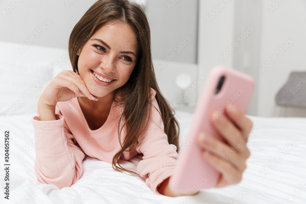 Cheerful lovely young girl wearing pajamas laying in bed Cheerful lovely young girl wearing pajamas laying in bed