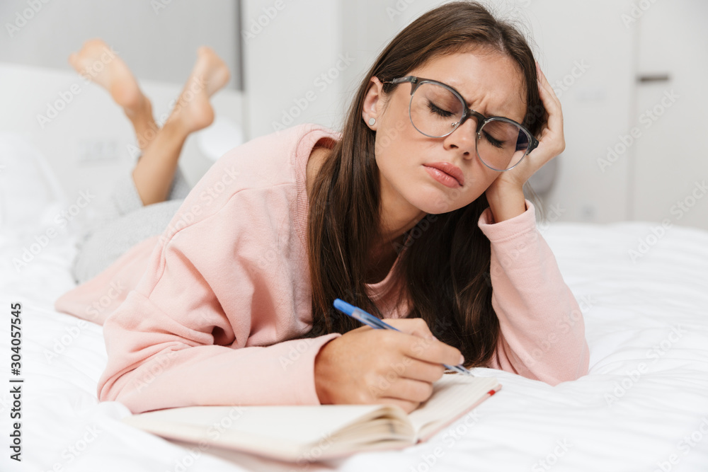 Upset lovely young girl wearing pajamas laying in bed Upset lovely young girl wearing pajamas laying in bed