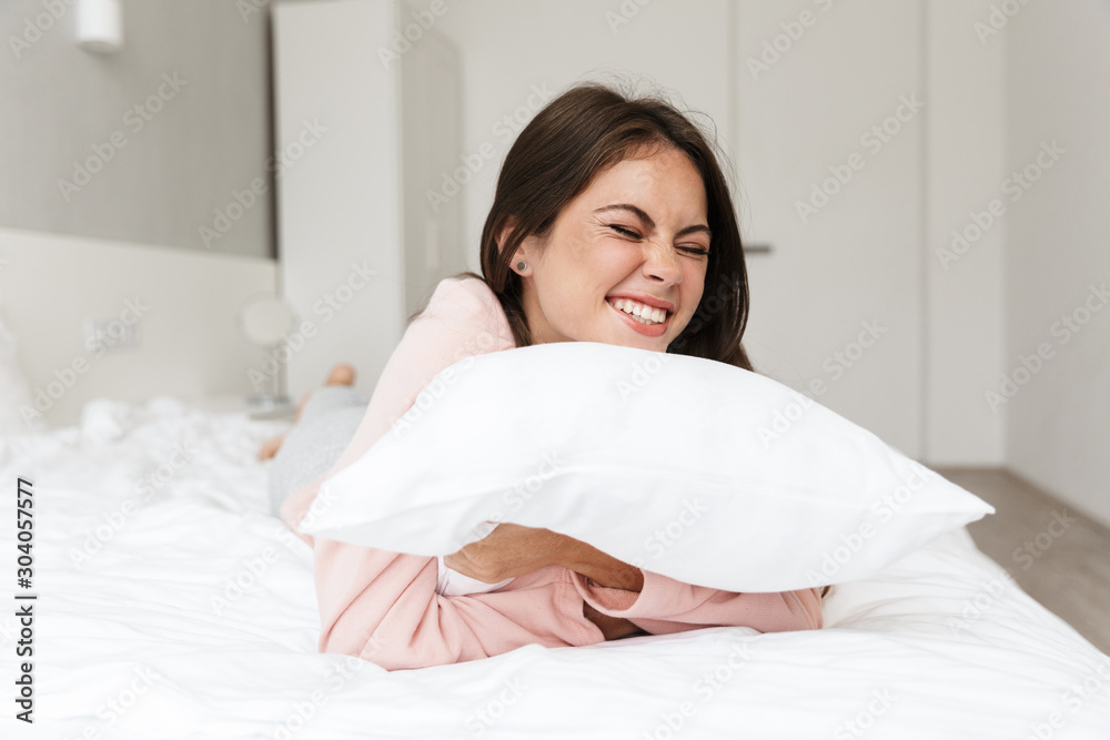 Cheerful lovely young girl wearing pajamas laying in bed Cheerful lovely young girl wearing pajamas laying in bed