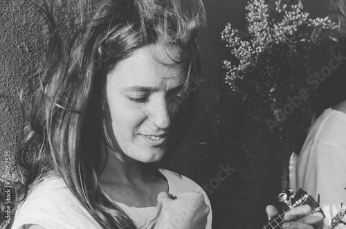 Black and white shot of Young woman playing ukulele on the street