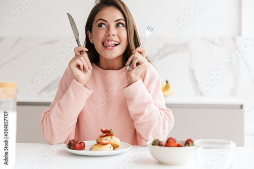 Beautiful smiling young girl having tasty healthy breakfast photo