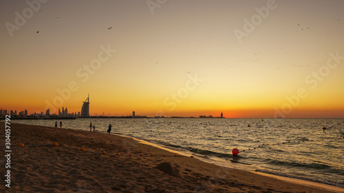 Orange sunset at the beach in Dubai showing iconic skyline 