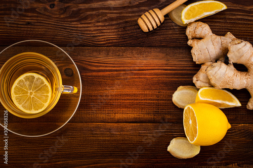 Cup of Ginger tea with lemon, honey and ginger root on a wooden background with copy space, top view