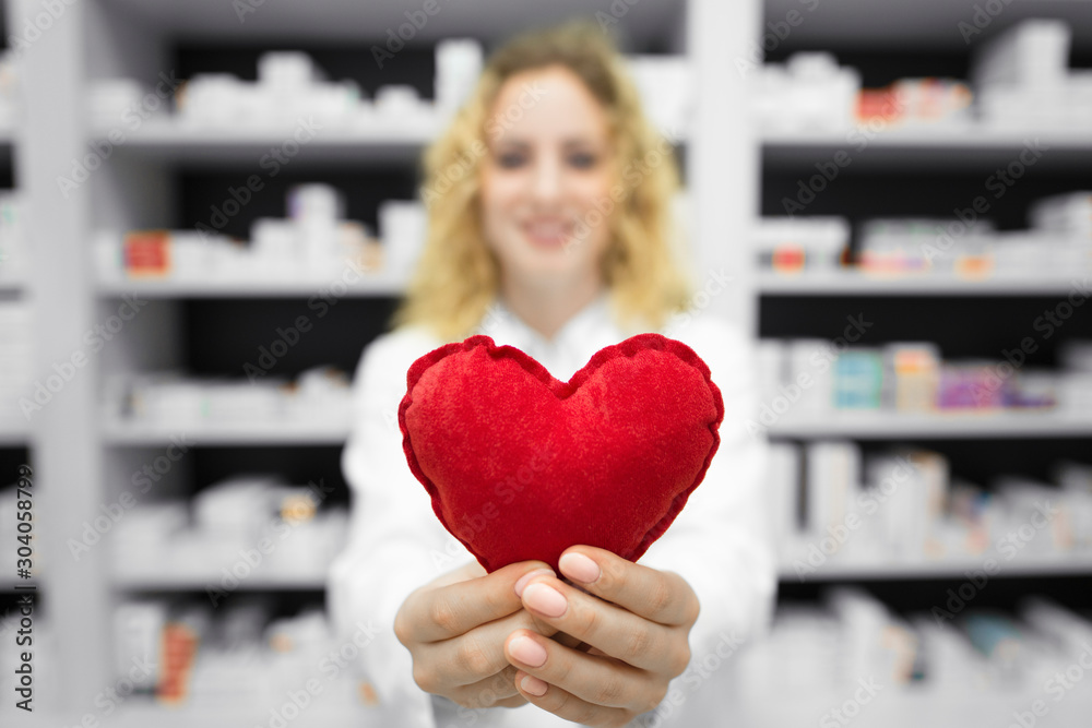 Heart medicines for cardiovascular problems. Pharmacist in drug store holding heart. In background shelf with medications. Pharmacy and health care. Heart medicines for cardiovascular problems. Pharmacist in drug store holding heart. In background shelf with medications. Pharmacy and health care.