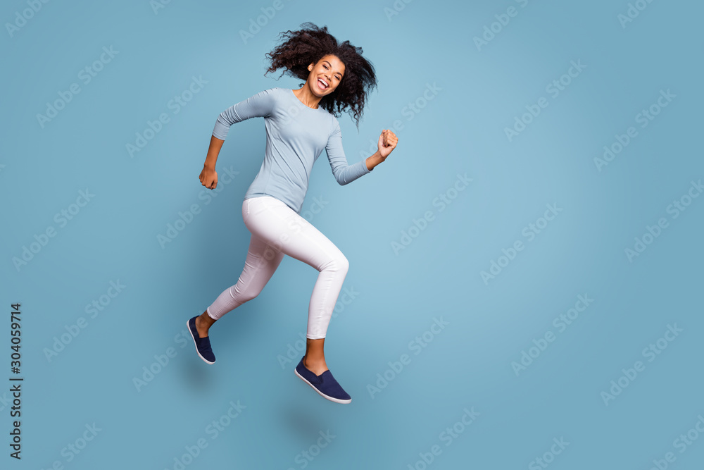 Full length body size turned photo of cheerful positive cute nice girlfriend wearing white pants running jumping footwear isolated pastel color background Full length body size turned photo of cheerful positive cute nice girlfriend wearing white pants running jumping footwear isolated pastel color background