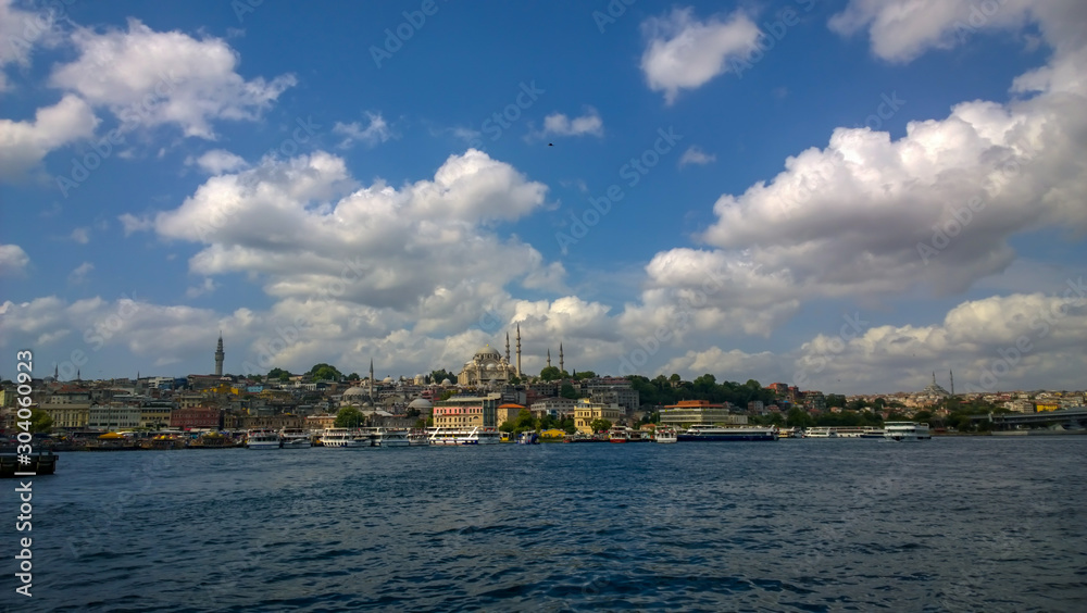 Beautiful coastal view from the sea of Istanbul, Turkey. Blue sky with clouds, blue sea and amazing historical architecture