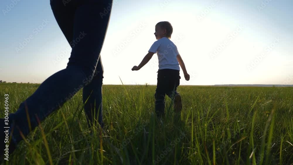 Young loving mom plays with her son outdoors. The child is happy and smiling. Happy family running around on the green grass, enjoying, having fun. The concept is a healthy lifestyle. Young loving mom plays with her son outdoors. The child is happy and smiling. Happy family running around on the green grass, enjoying, having fun. The concept is a healthy lifestyle.