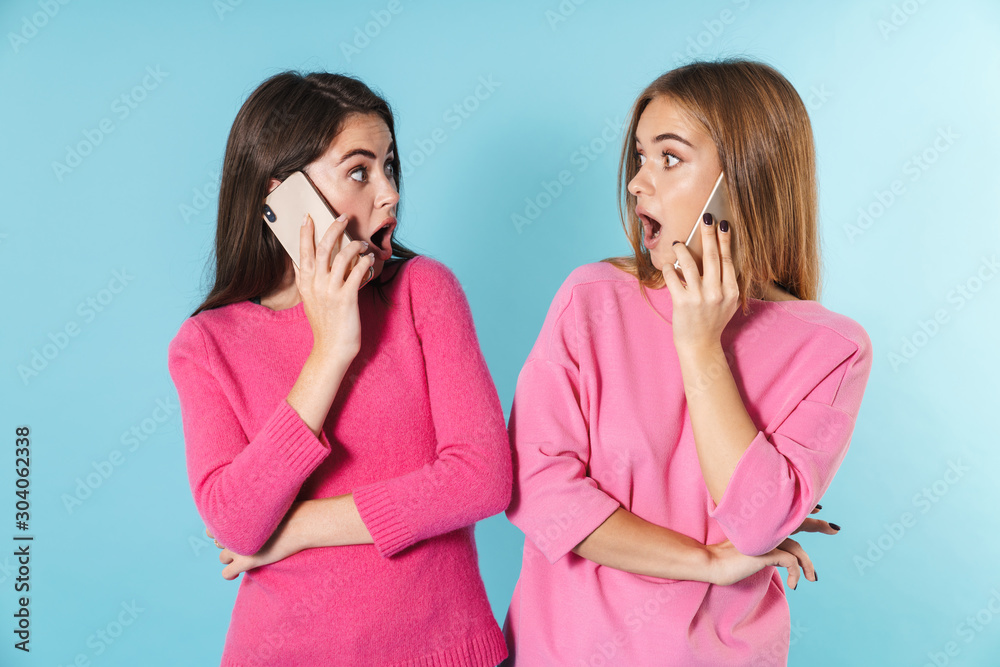 Photo of shocked young women talking on cellphones Photo of shocked young women talking on cellphones