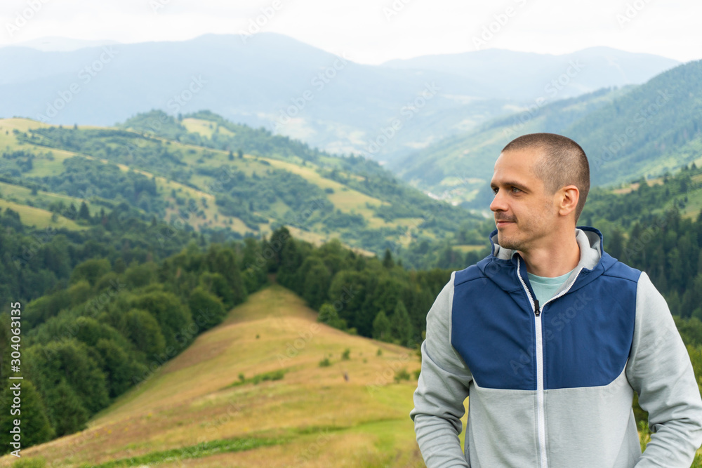 Portrait of adult man standing with mountain landscape