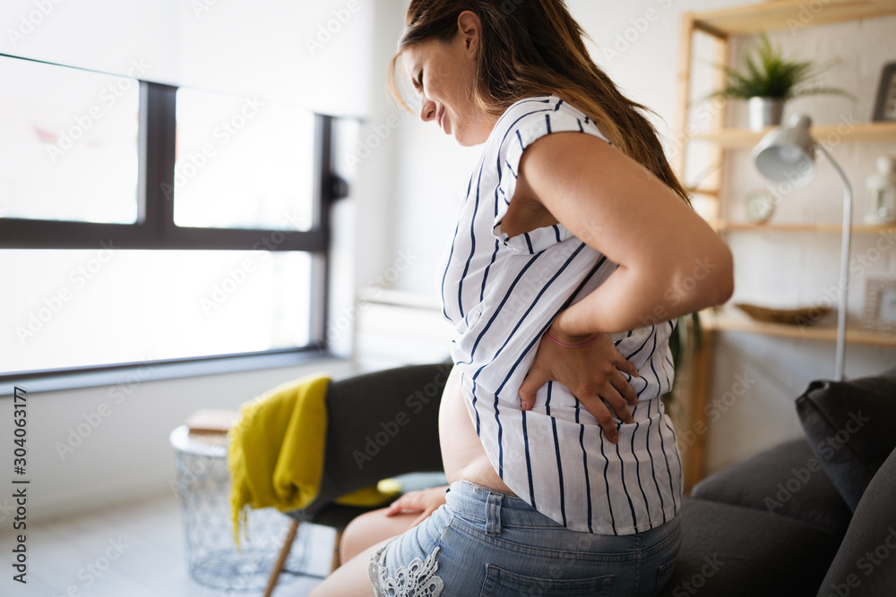 Beautiful pregnant woman expecting baby feeling tired with back pain - obrazy, fototapety, plakaty 