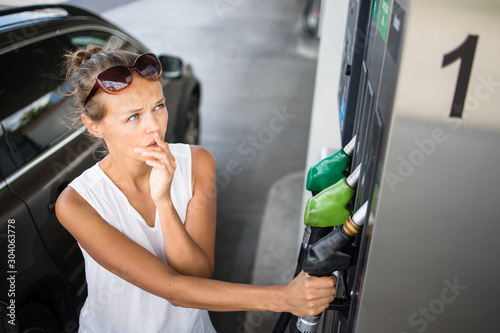 фотографія Young woman pumping gas at gas pump