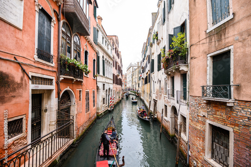 09.10.2019 Venice, Italy, gondola with tourists floating on a narrow channel with turquoise water. The historic center of the city, Windows with wooden shutters. © Vladimir