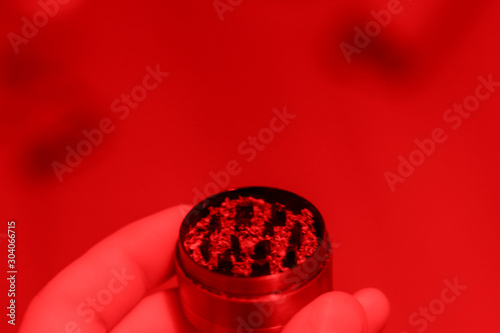 Smoking marijuana grinder in red lighting. Close-up with bokeh effect. Copy space for text about weed and drug use