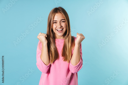 Photo of happy blonde woman looking at camera with winner gesture