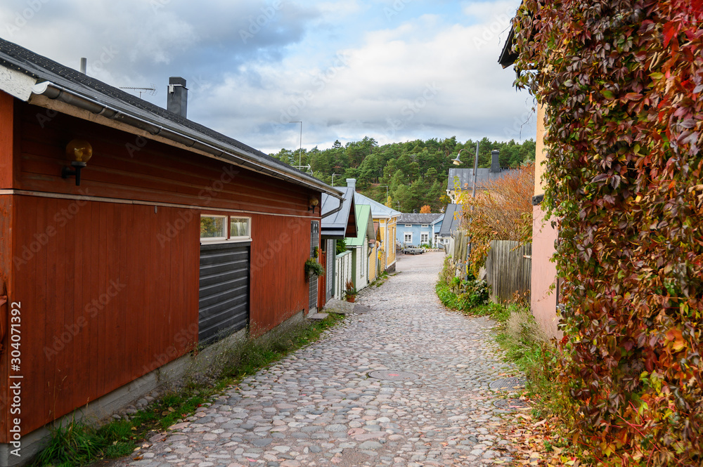 Street with cobblestones and autumn yellow and red leaves. Beautiful seasonal landscape. Porvoo, Finland.