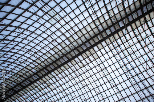 Double exposure of structural glazing. Generic modern architecture fragment with glass ceiling, roof or wall made of transparent facade panels. Abstract geometric background with complex grid pattern.