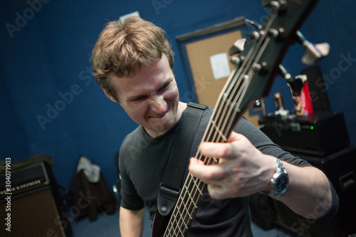 male musician playing rock music on bass guitar in the Studio
