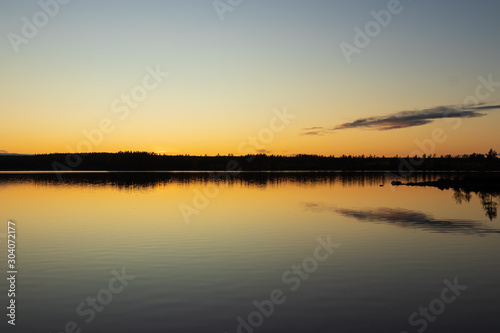 Fototapeta Naklejka Na Ścianę i Meble -  Sunset over a lake inside a forest creating a perfect reflection in the water. 