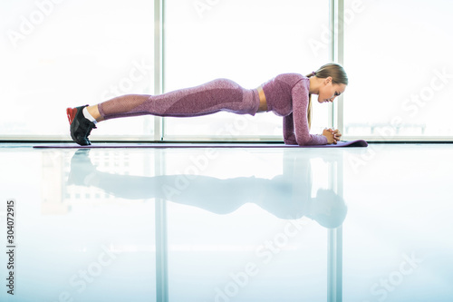 Slim fitnes young girl with ponytail doing planking exercise indoors at studio gymnastics.