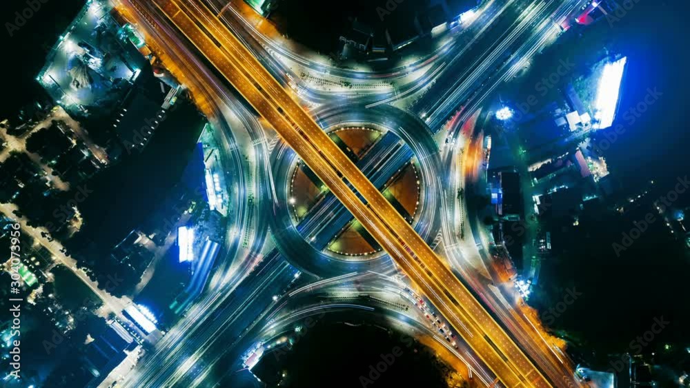 Hyperlapse timelapse of night city traffic on 4-way stop street intersection circle roundabout in bangkok, thailand. 4K UHD horizontal aerial view.