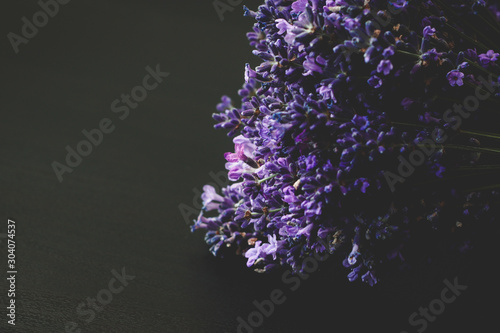 A beautiful lavender on a black wooden background. Dark lilac and blue flowers of lavender.