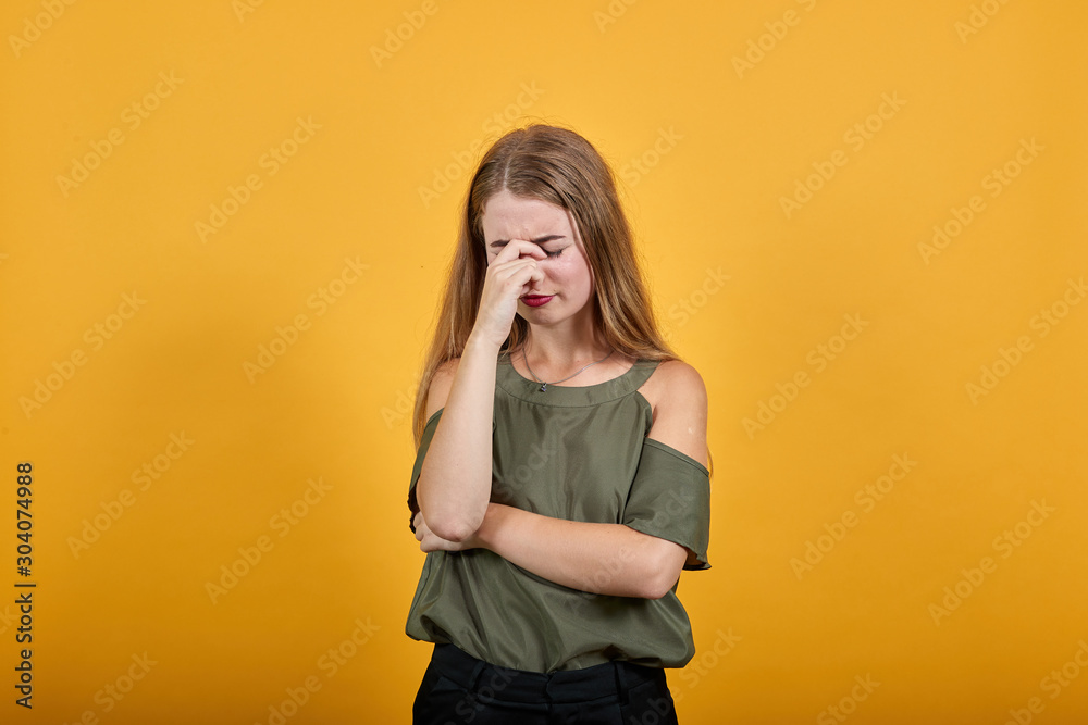 Portrait of confused young woman with closed eyes and covering nose with hand, like crying isolated on orange wall background in studio. People sincere emotions, lifestyle concept. Portrait of confused young woman with closed eyes and covering nose with hand, like crying isolated on orange wall background in studio. People sincere emotions, lifestyle concept.