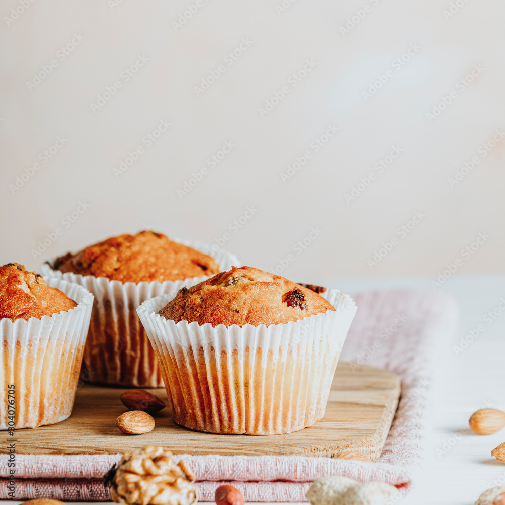 Vanilla caramel muffins in paper cups on white wooden background. Vanilla caramel muffins in paper cups on white wooden background.