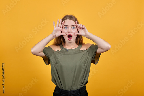 Attractive young caucasian woman shocked and scared, keeping hand on eyes on isolated orange background wearing nice fashion pastel shirt © Petro
