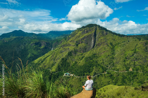 woman sitting on stone on Mini Adams peak looking on green mountains of Sri Lanka photo
