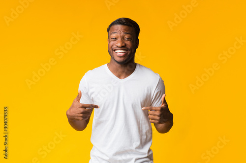 Black Man Pointing Fingers At Himself Smiling Over Yellow Background