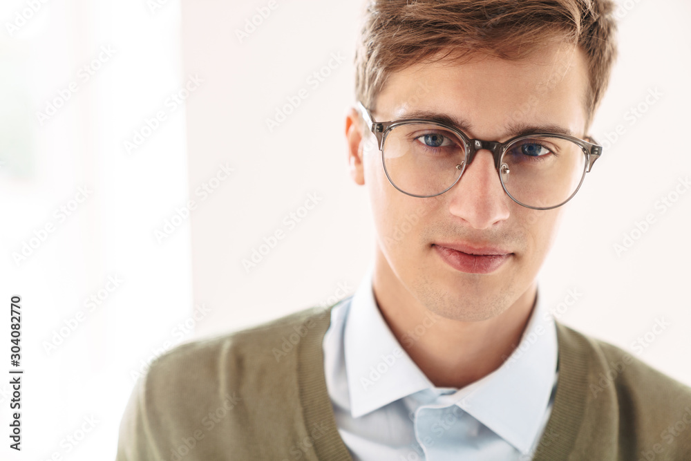 Serious young guy student posing indoor in eyeglasses.