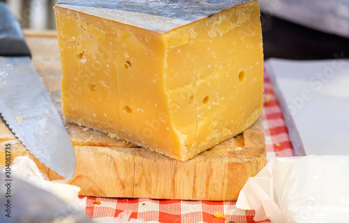 Tasty aged gouda cheese on wooden cutboard sold at farmers market photo