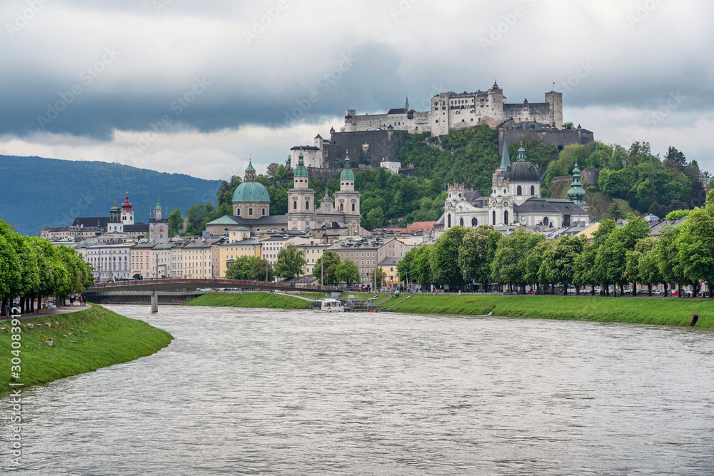 Classic panoramic view of historic city of Salzburg with famous Hohensalzburg Fortress and idyllic Salzach river on a beautiful day in spring with a dark dramatic cloudscape, Salzburger Land, Austria