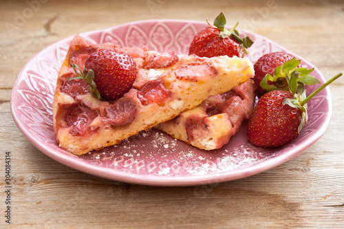 Round strawberry pie with fresh strawberries slice on plate dish on wooden table background