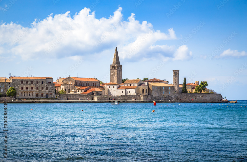 Scenic panoramic view of the historic skyline of adriatic town of Porec with deep blue water on a sunny day with beautiful clouds in summer, Istria, Croatia