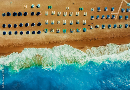 sandy beach with sun beds umbrellas in neat rows on the tsambika beach Rhodes Greece. The concept of a holiday resort view from drone
