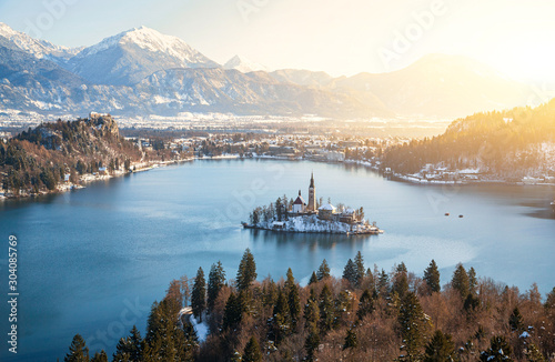 Panoramic aerial view of famous Bled Island (Blejski otok) at scenic Lake Bled with Bled Castle (Blejski grad) and Julian Alps in the background on a beautiful sunny day in winter, Slovenia photo