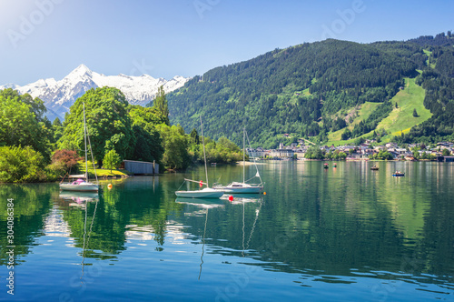Scenic panoramic view of idyllic Zeller lake with old town Zell am See and snow-capped alpine mountain top Kitzsteinhorn on a beautiful sunny day with blue sky in springtime, Salzburger Land, Austria