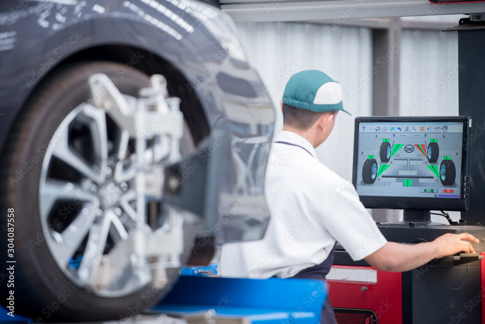 Fototapeta premium Auto mechanic installs sensors during suspension adjustment. Wheel alignment work at a car repair station