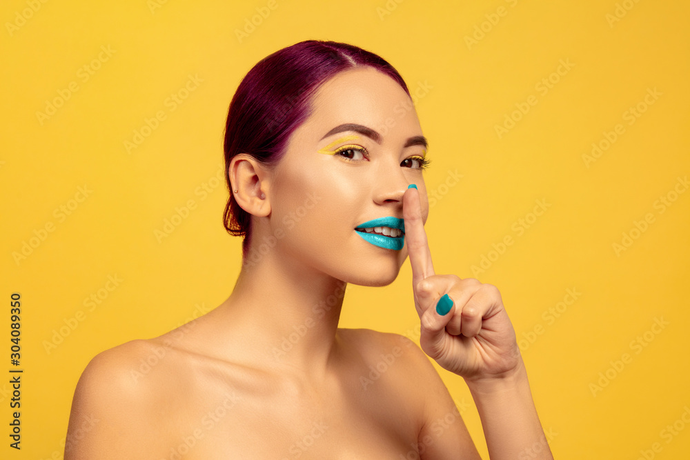 Portrait of beautiful woman with bright make-up, hair and manicure on yellow studio background. Stylish and fashionable make, hairstyle. Colors of summer. Beauty, fashion, ad concept. Whispers secrets Portrait of beautiful woman with bright make-up, hair and manicure on yellow studio background. Stylish and fashionable make, hairstyle. Colors of summer. Beauty, fashion, ad concept. Whispers secrets