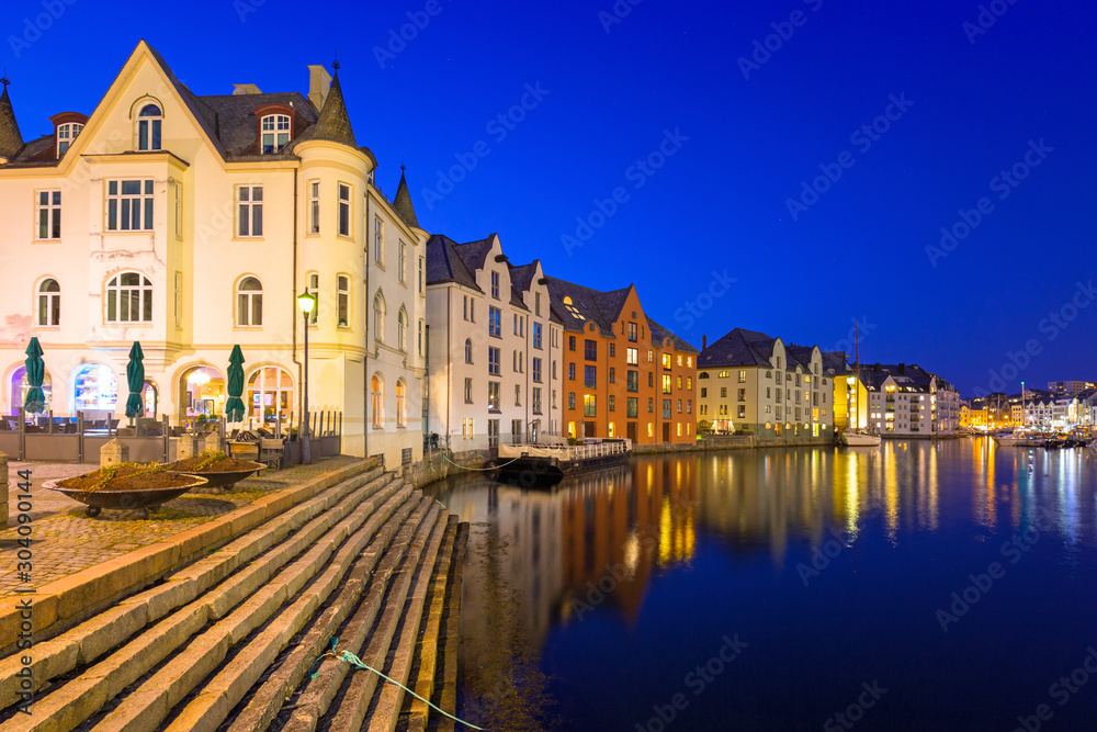 Architecture of Alesund city reflected in the water at night, Norway