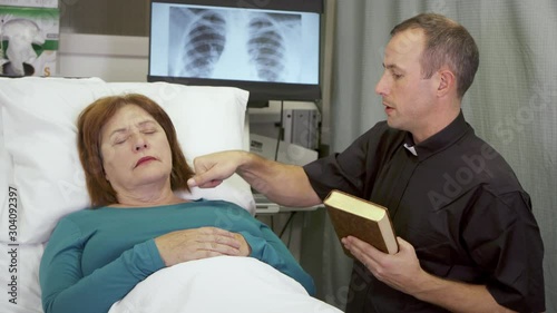 A priest delivers last rites to a woman who is near death in the hospital.