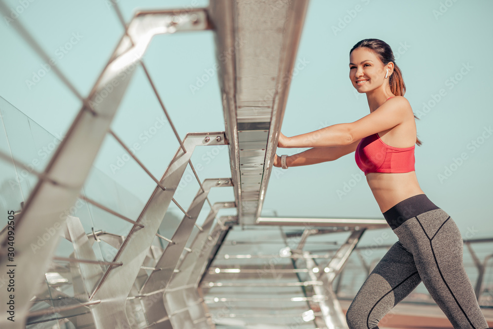 smiling female jogger woman warming before training on the city bridge smiling female jogger woman warming before training on the city bridge
