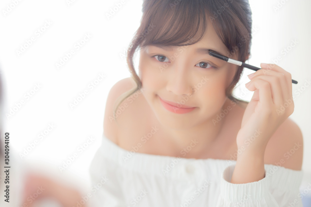 Beautiful young asian woman applying makeup eyebrows brush, beauty asia girl using cosmetic for make up style looking mirror at home, fashion female tweezing with natural, lifestyle concept.