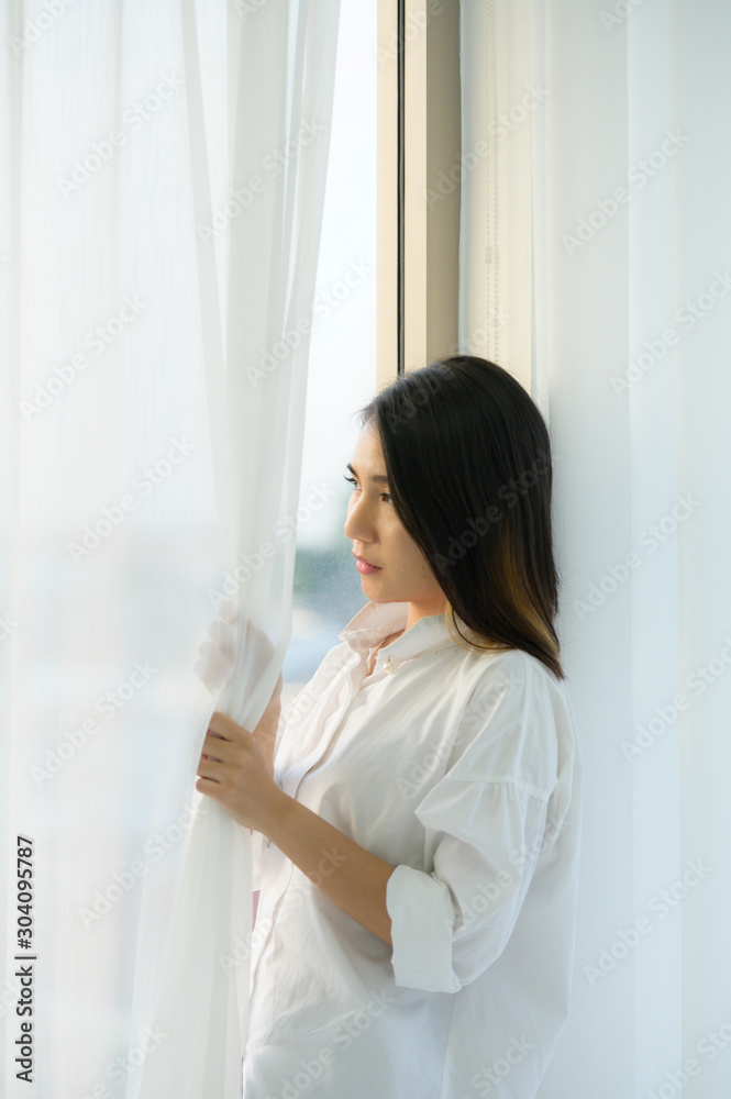 Young woman asian people in the bedroom with white curtains and the morning atmosphere when the sun shines.