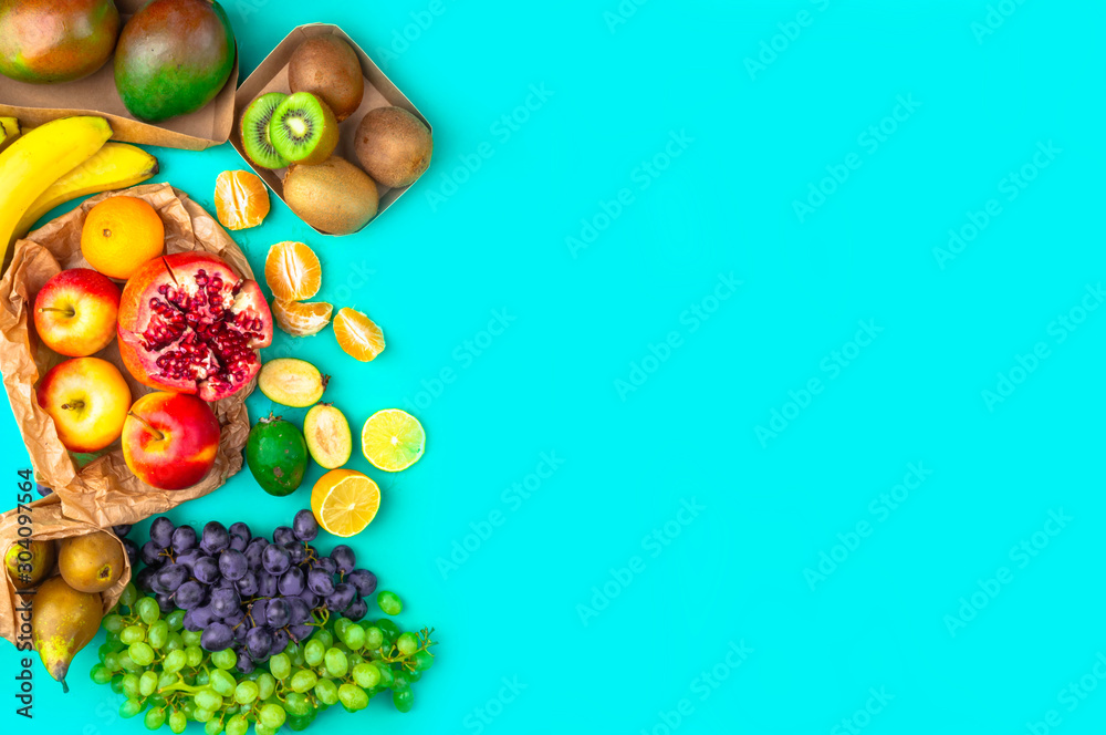 Fruits and vegetables rich in antioxidants, vitamin and fiber on blue background. Zero waste food shopping, eco natural paper bags Flat lay style
