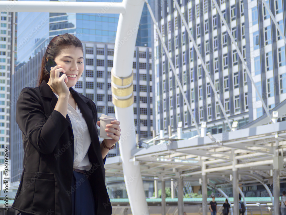 Asian business woman holding coffee paper cup enjoy calling smartphone at outdoor office. Asian business woman holding coffee paper cup enjoy calling smartphone at outdoor office.