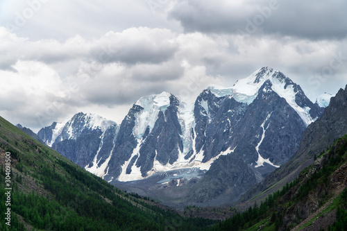 Landscape of snowy mountain peaks in the clouds. The concept of global warming and glacier melting. © Nick Vakhrushev